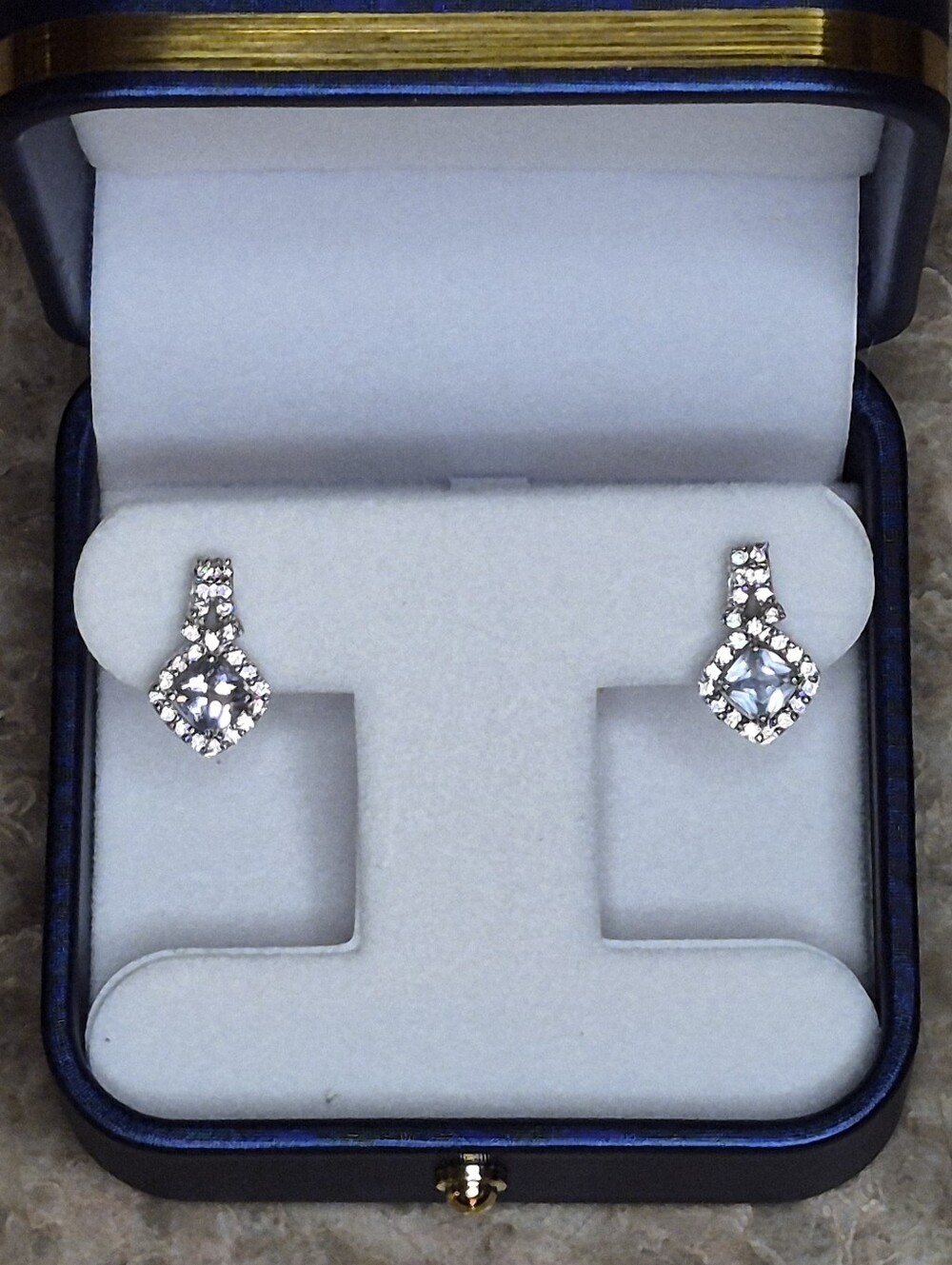 Brighton drop earrings feature a striking cushion-cut blue crystal center